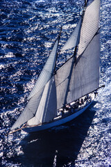 Flight over classic yacht sailing regatta in mediterranean coastal setting.