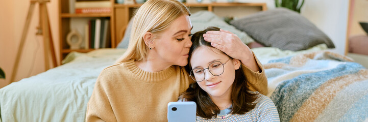 Warm moment between mother and daughter in cozy bedroom as mother lovingly kisses daughter's...