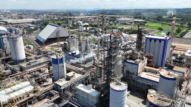 Vis&atilde;o a&eacute;rea em 4K de uma ind&uacute;stria de papel e celulose com chamin&eacute;s e caldeiras em opera&ccedil;&atilde;o. Imagem capturada por drone, destacando a planta industrial e suas estruturas