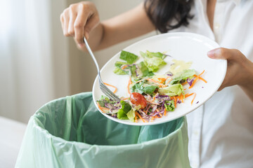 Compost from leftover food asian young housekeeper woman, female hand holding salad bowl use fork...