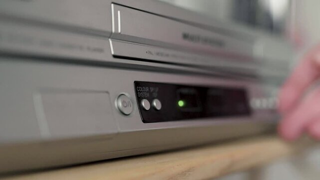 Close up of a hand puting a videotape into video player. Retro vhs cassete in a player.