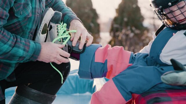 Dad putting skates on outdoors at rink