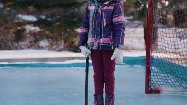 Tilt up young girl playing hockey on rink