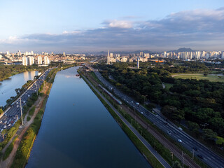Obraz premium Rising sun on a river within the metropolis of São Paulo with the Pinheiros riverside.