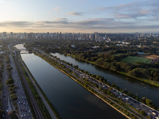 Obraz premium Rising sun on a river within the metropolis of São Paulo with the Pinheiros riverside.