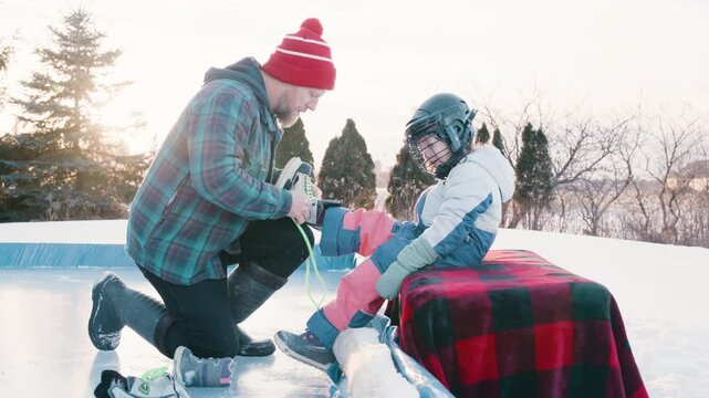 Daddy daughter lacing up skates at the rink