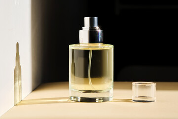 Perfume on a beige background in the rays of bright sun with beautiful highlights.