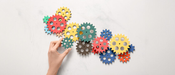 Hand with wooden gears on light background