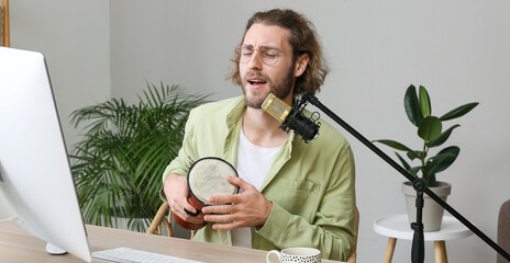 Young man with drum singing in microphone at home