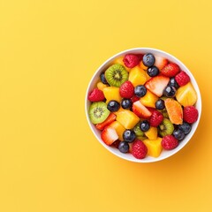A colorful bowl of mixed fruits including berries, kiwi, and oranges against a bright yellow background.