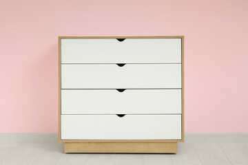 White chest of drawers near pink wall in room