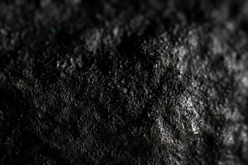 Extreme close up of painted in black handmade paper clay with a structure and rough texture. Paper recycling. Selective focus, shallow depth of field.
