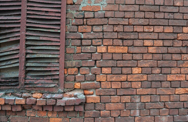 Weathered brick wall texture with peeling paint and rusted shutters