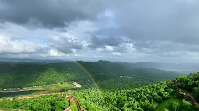 The view from Jaigarh Fort overlooks Amer Fort in Jaipur, offering a stunning of historic architecture and scenic landscapes, especially with a rainbow in the sky.