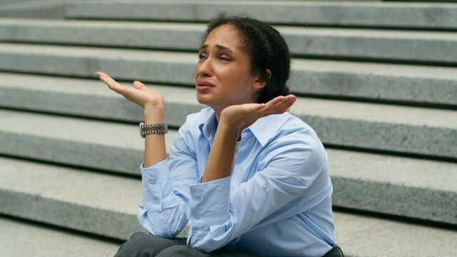 Depressed stressed African American businesswoman talking to God heaven upset business woman girl female employer suffering failure job lost in city sit on stairs headache unemployment crisis problem