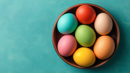 A bowl filled with colorful, decorated eggs sits on a turquoise surface, creating a vibrant and festive atmosphere.