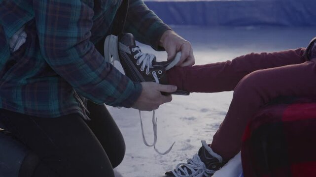 Father daughter getting ready for skating on hockey rink