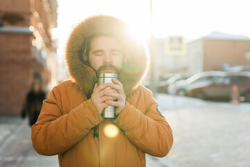 Man warming up with hot drink on cold winter morning outdoors. Copy space. Comfort, routine, and...