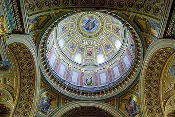 The ornate domed ceiling of the Budapest Basilica is decorated with classical motifs and figures....