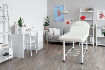Interior of light medical office with couch, sofa and doctor's workplace