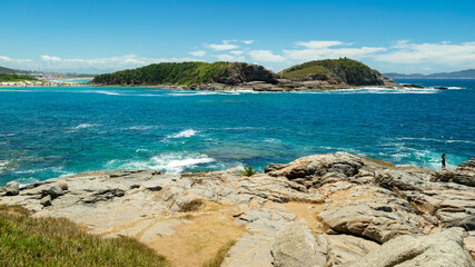Part of Praia das Conchas. With crystal clear waters, blue sky, lots of rocks and mountains in the background. Near the city of Cabo Frio, Rio de Janeiro.
