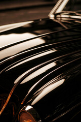 Sleek Black Car Hood with Striking Reflections in Warm Tones Highlighting Automotive Elegance