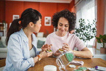 female friends share skincare moment use face cream relax together