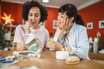 female friends share skincare moment use face cream relax together