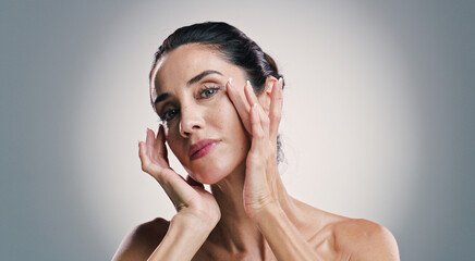 Obraz premium Natural skincare, portrait and woman with glow, touch and results of collagen treatment for anti aging. Mature model, confident face and cosmetics, dermatology and beauty on gray studio background