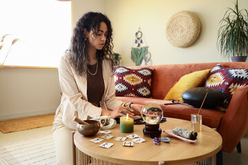Young African-American witch reading tarot cards at home