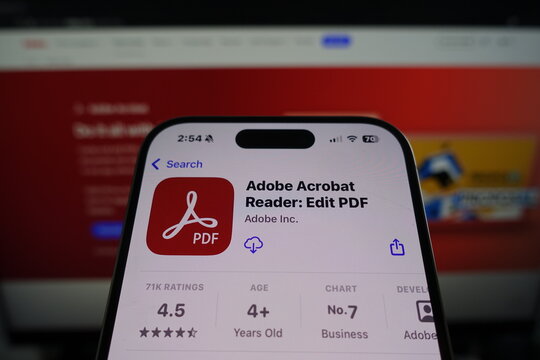 Kiel, SH, Germany March 27 2025: Adobe Acrobat Reader by Adobe Inc in the App Store on smartphone screen with company website in background showcasing services