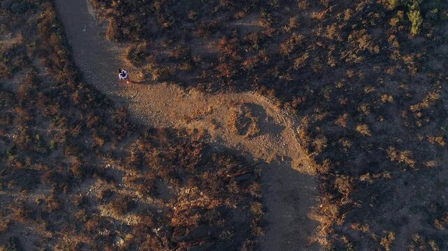 Aerial top down view of trail running man jogging on rugged mtn path