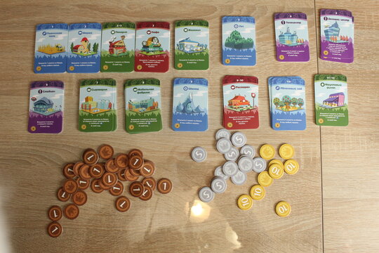Mozyr, Belarus, April 10 2024: board game Machi Koro. Preparation for the game. Machi Koro's Upgrade and Coin Cards