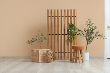 Stylish interior of living room with cozy chair, houseplant and wooden folding screen