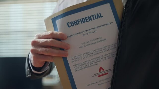 Spy or agent taking out secret confidential envelope with classified documents from his jacket in office setting. Mysterious person revealing stolen file folder with sensitive government information