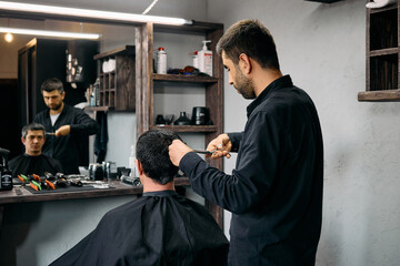 A hairdresser meticulously styles a customer's hair at a contemporary barbershop. The atmosphere is...