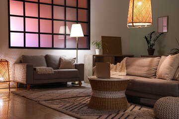 Interior of cozy living room with sofas, table and glowing lamps