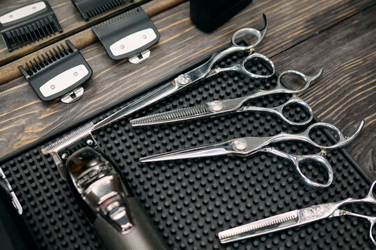 Various barber tools are neatly organized for haircutting, showcasing scissors, clippers, and combs ready for use in a bustling barbershop environment
