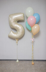 foil beige number 5 balloon and bunch of delicate helium balloons, decorations for a girl's birthday
