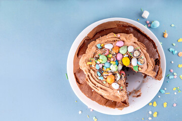 Easter Egg Nest Chocolate Cake. Sweet Easter cake with crushed chocolate eggs, traditional holiday baking recipe idea, on festive decorated table copy space