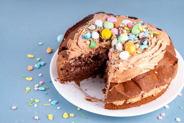 Easter Egg Nest Chocolate Cake. Sweet Easter cake with crushed chocolate eggs, traditional holiday baking recipe idea, on festive decorated table copy space