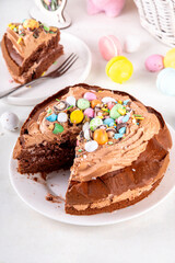 Easter Egg Nest Chocolate Cake. Sweet Easter cake with crushed chocolate eggs, traditional holiday baking recipe idea, on festive decorated table copy space