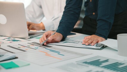Business professionals engage in collaborative data analysis with reports and charts on a desk, using a laptop in a modern office, enhancing teamwork and productivity. SACTR