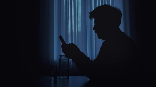 Silhouette of a Man Engaged with Smartphone in Dim Light