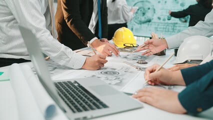 A diverse team of engineers and architects collaborates on project plans in a modern office setting, surrounded by construction tools and documents, emphasizing teamwork. SACTR
