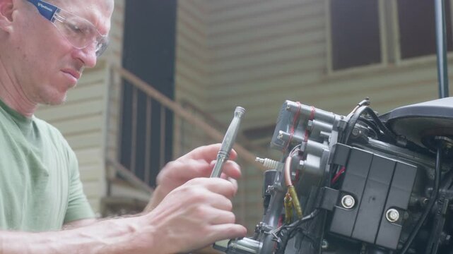 Boat outboard motor maintenance by an Australian Caucasian male. Fitting spark plugs, tool use, clip 36