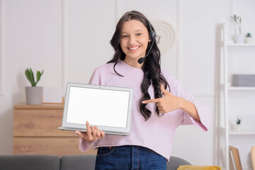 Teenage girl in headset with blank laptop working online at home