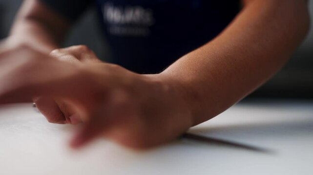 Close up view in slow motion of two hands smashing and crushing a garlic clove under a cinematic atmosphere.