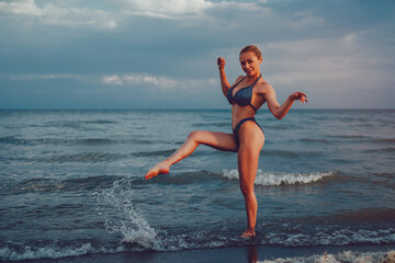 Young fitness woman posing on lake shore on summer day