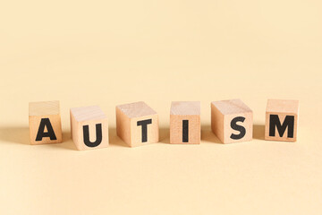 Word AUTISM made of wooden cubes on beige background